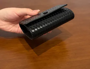 Primo piano della struttura laterale e inferiore di un portafoglio nero intrecciato