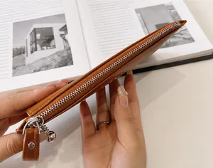Dettaglio ravvicinato della cerniera argentata di una pochette in pelle marrone