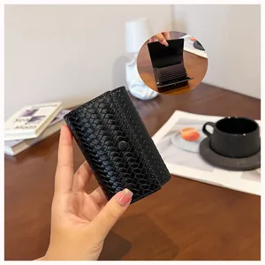 Primo piano di un porta carte in pelle intrecciata nera con fessure interne in stile fisarmonica.