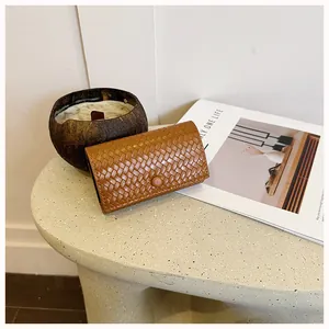 Dettaglio ravvicinato della trama intrecciata marrone di una pochette vintage da donna