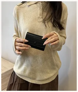 Portafoglio da donna in pelle intrecciata nera tenuto da una modella elegante