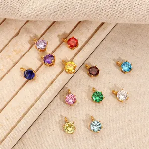 Vista dettagliata di dodici ciondoli in zirconia colorata placcati oro 18K su vassoio beige