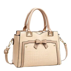 Elegant beige crocodile embossed handbag featuring a bow detail and top handles