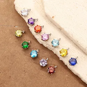 Dettaglio di ciondoli rotondi in zircone colorato con montatura in acciaio su pietra.