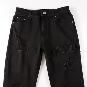 Close-up of mens black ripped jeans showing detailed distressing and frayed denim texture.