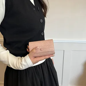 Elegante portafoglio intrecciato rosa polvere, accessorio estivo chic per donne.