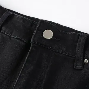 Close-up of metal button and stitching detail on black high street denim jeans.