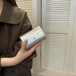 Elegante portafoglio in pelle intrecciata argento da donna, tenuto in mano con stile