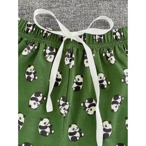 Primo piano di pantaloncini del pigiama verde da donna con stampa panda e fiocco bianco