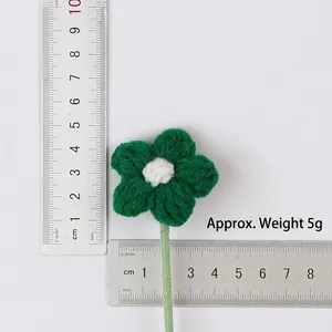 Detail view of a hand-knitted green wool flower with measurements and 5g weight