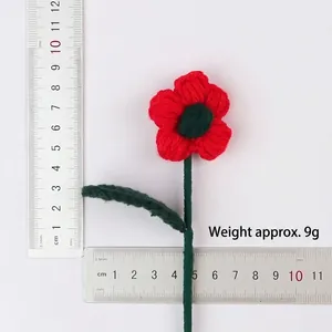 Detailed view of handmade knitted red yarn flower with ruler scale and weight information.