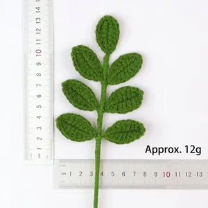 Close-up detail of a handmade knitted green leaf branch with weight and size reference markings