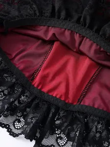 Close-up detail of gothic black lace trim and dark red silky fabric patchwork.