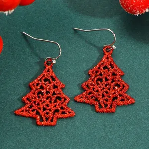 Close-up of red glitter Christmas tree earrings with an intricate hollowed pattern