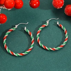 Macro detail showing the vibrant red and green glitter texture on festive Christmas hoop earrings