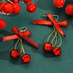 Close-up of festive red ribbon bow and bell drop earrings for Christmas season