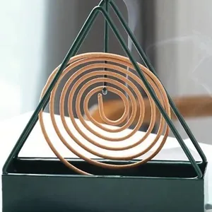 Nahaufnahme eines dunkelgrünen dreieckigen Weihrauchhalters mit brennender Spirale