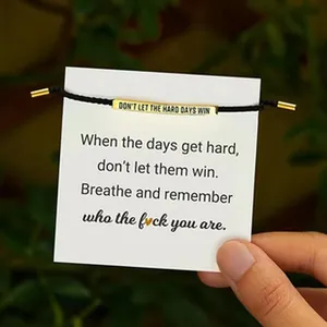 Close-up of stainless steel cord bracelet with motivational engraved bead on card