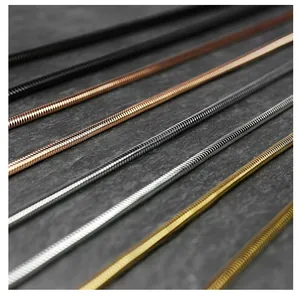 Detailed close-up of multi-color titanium steel snake bone chains on a gray surface