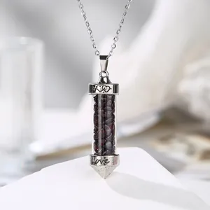 Close-up of a silver-colored cylindrical necklace pendant filled with garnet crushed stones.