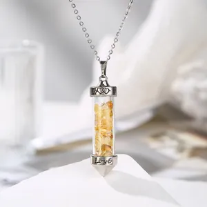 Macro view of citrine crushed stones in a cylindrical glass pendant engraved with Love