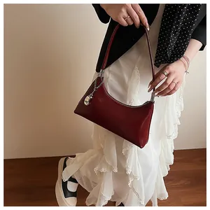 Schicke dunkelrote Achseltasche kombiniert mit weißem Rüschenkleid für einen Retro-Look