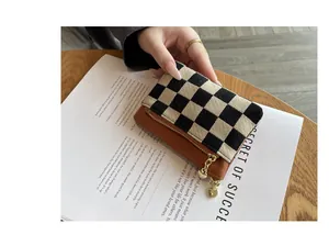 Hand die een chique mini-portemonnee vasthoudt met schaakbordpatroon en hartdetail