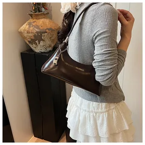 Nahaufnahme einer glänzenden dunkelbraunen Unterarmtasche getragen zu einem Retro-Outfit