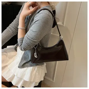 Elegante dunkelbraune Vintage-Baguette-Schultertasche, getragen zu einem grauen Cardigan