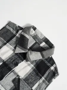 Detailed close-up of grey and white plaid wool sleeveless vest collar with black buttons.