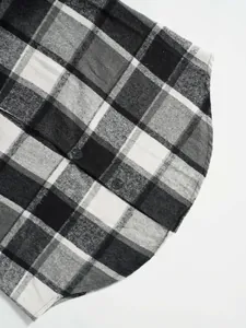 Close-up detail of black and white plaid wool vest with curved hem and buttons