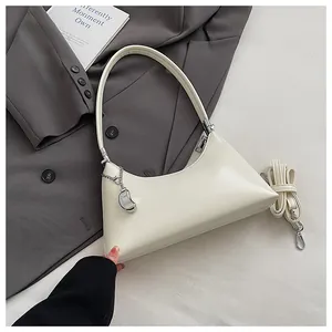 Detailansicht einer cremeweißen minimalistischen Unterarmtasche mit silbernem Anhänger