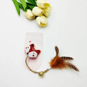 Detailopname van een vosvormig kattenknuffeltje met veren, henneptouw en een goud belletje.