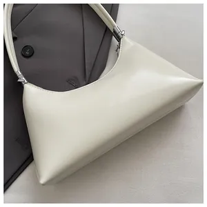 Nahaufnahme der glatten Textur einer minimalistischen cremefarbenen Unterarm-Schultertasche