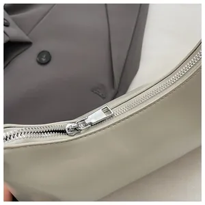 Nahaufnahme der beigen Leder-Unterarmtasche mit silbernem Metallreißverschluss im Detail.