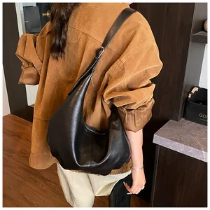 Detailansicht einer schwarzen Vintage-Knödeltasche, getragen mit einer braunen Jacke.