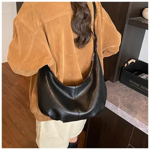 Detailaufnahme der schwarzen Hobo-Tasche im Vintage-Stil, getragen über der Schulter.