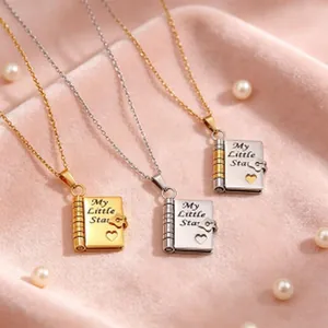 Detailansicht von drei Herz-Buch-Anhängern in Gold, Silber und Bicolor auf rosa Samt.
