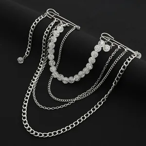 Détail d'une broche à chaîne argentée multicouche avec perles transparentes sur noir.