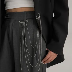 Vue détaillée d'une broche à plusieurs chaînes argentées décorant un blazer et un pantalon.