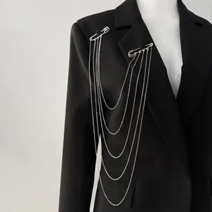 Vue détaillée d'une broche à chaîne argentée multicouche sur un blazer noir