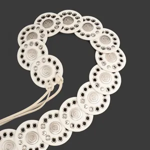 Detailed close-up of white ethnic belt featuring silver grommets and engraved medallions