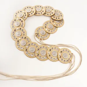 Macro detail of bohemian retro waist belt featuring gold hollow discs and cotton cords