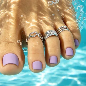 Detail showing silver-tone heart and carved toe rings on a foot in pool water.