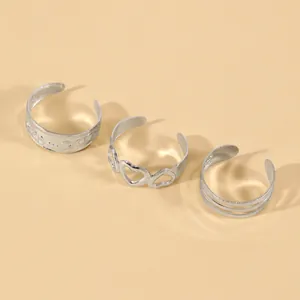 Detailed macro view showing three silver open toe rings with heart and layered designs