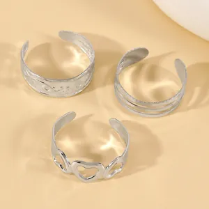 Detail view of three silver-tone open toe rings with heart and embossed line patterns.