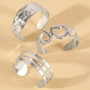 Detailed view of three silver-tone adjustable toe rings with heart and striped patterns.