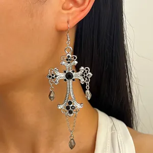 Primo piano di orecchino a croce gotica in argento con pietre nere e pendenti a goccia