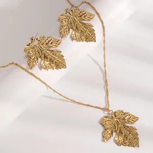 Macro view of textured golden maple leaf pendant necklace and matching earrings set.