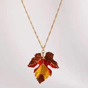 Detailed close-up of a retro color-block maple leaf pendant necklace with autumn vibes